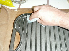 Appling a light coating of seasoning to cast iron on all surfaces